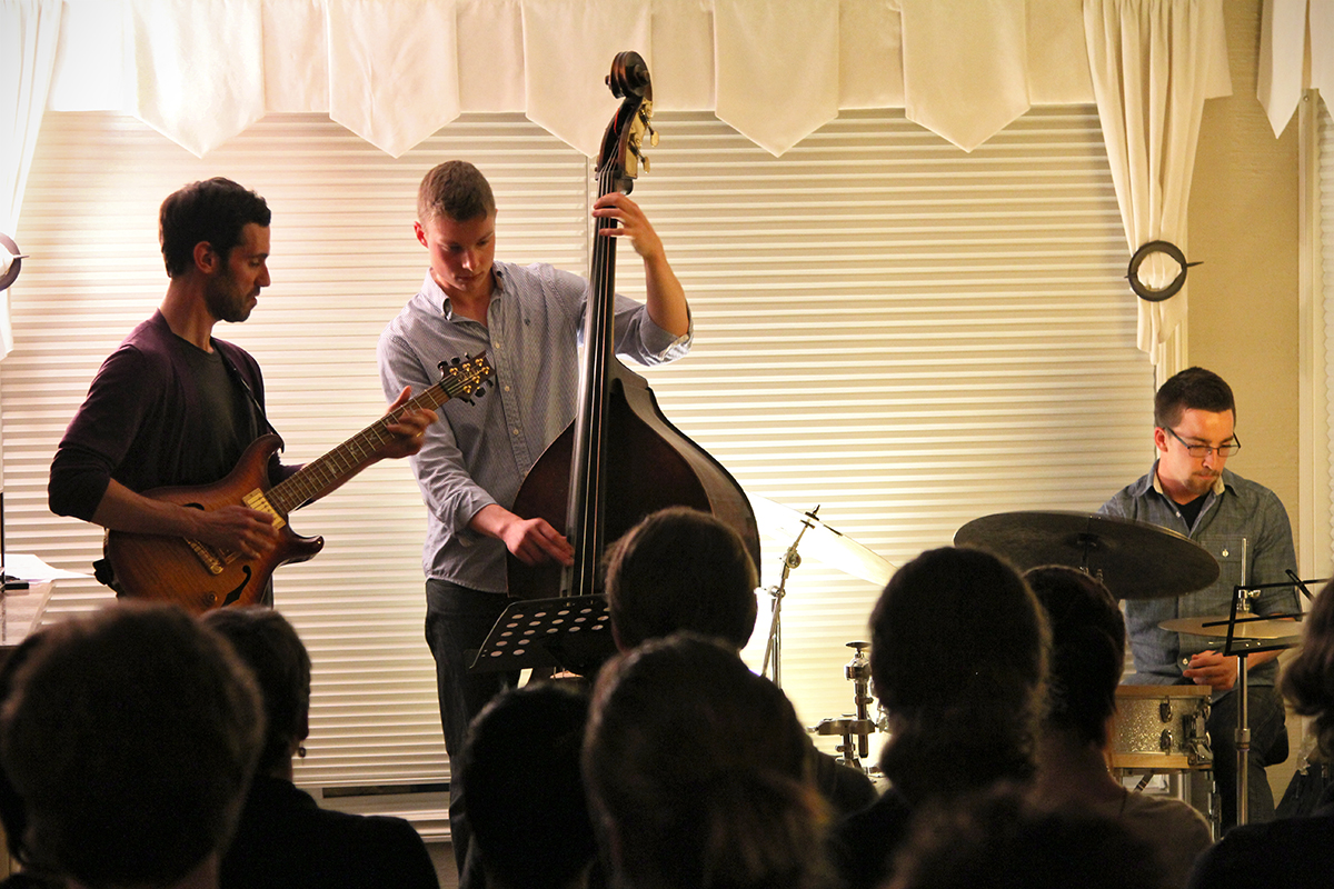 The Soren Nissen, Ian Wright and Nate Renner trio. The living room audience looks on as the trio plays an original tune by Renner. Photo taken Friday, May 17, 2013.
